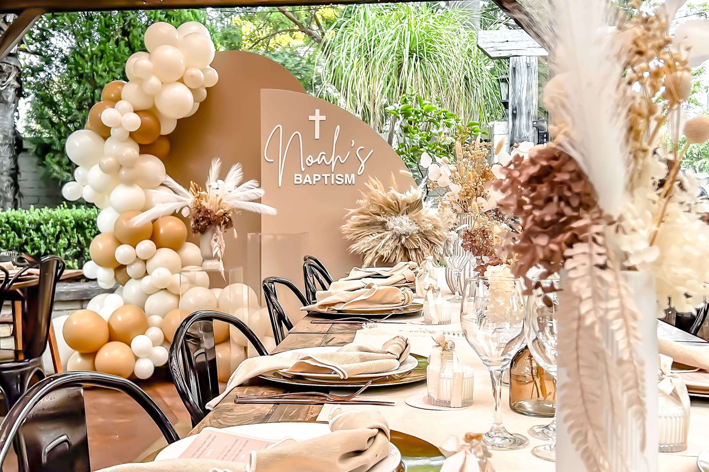 beige and brown arch backdrops with balloons and flowers behind boho table setting