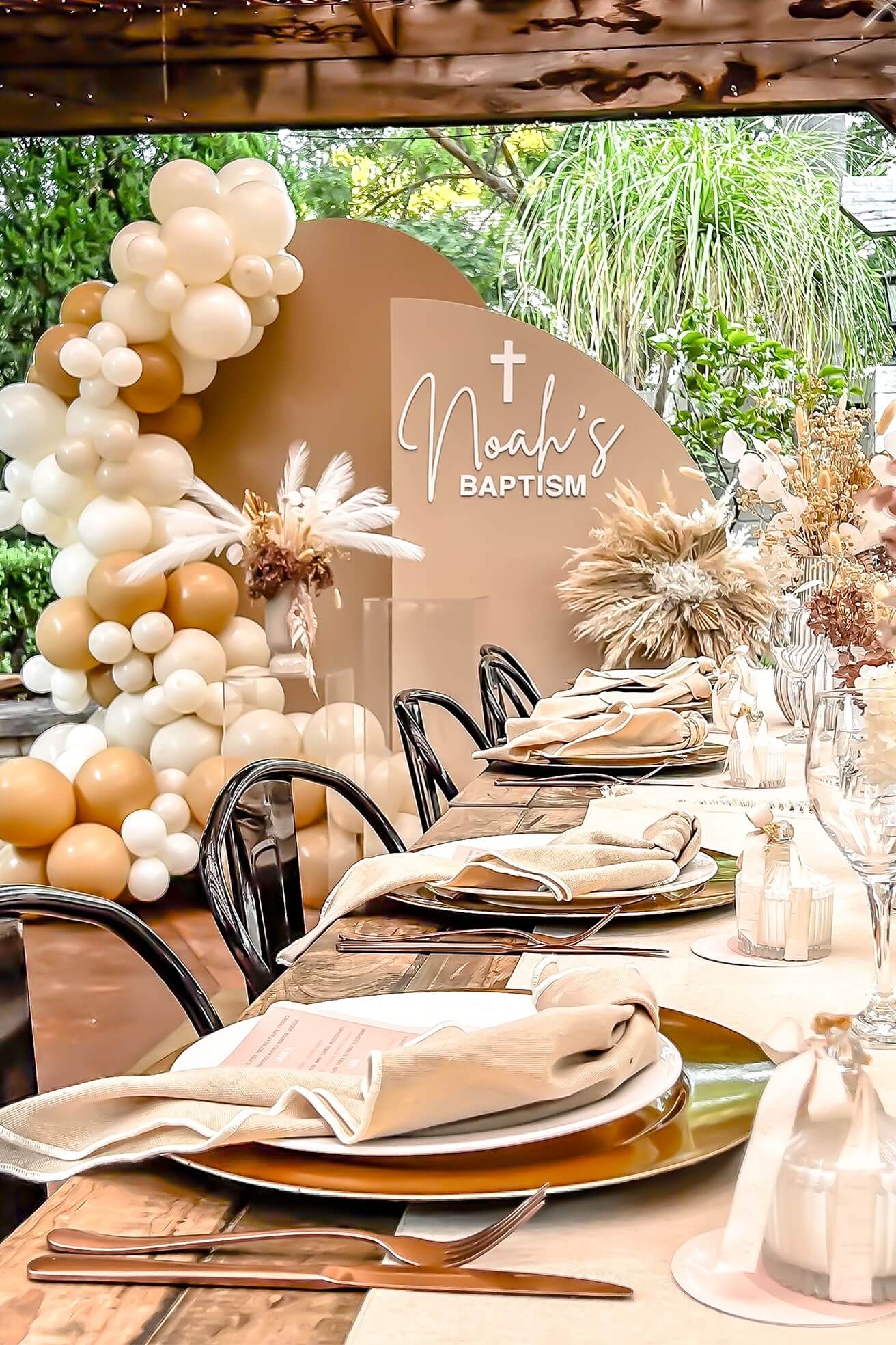 beige and brown arch backdrops with balloons and flowers behind boho table setting