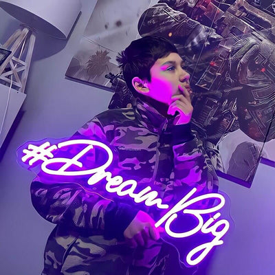 boy holding purple dream big neon sign in bedroom