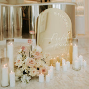 gold welcome sign mirror with white candles and flowers on floor