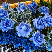 mix of light and dark blue roses and baby's breath hanging on white mesh backdrop