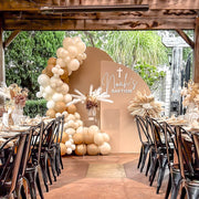 boho flower arrangement attached to beige backdrops with balloon garland at baptism event