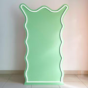 green curly backdrop board with white trimming standing on floor