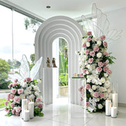 white 3d rainbow arch backdrop with dusty pink and white rose flower arrangement towers and led butterflies