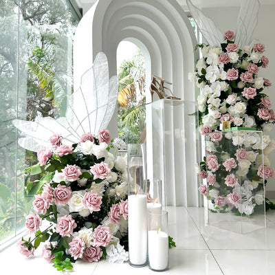 dusty pink and white rose flower arrangements in front of white 3d arch backdrop with white sand candles