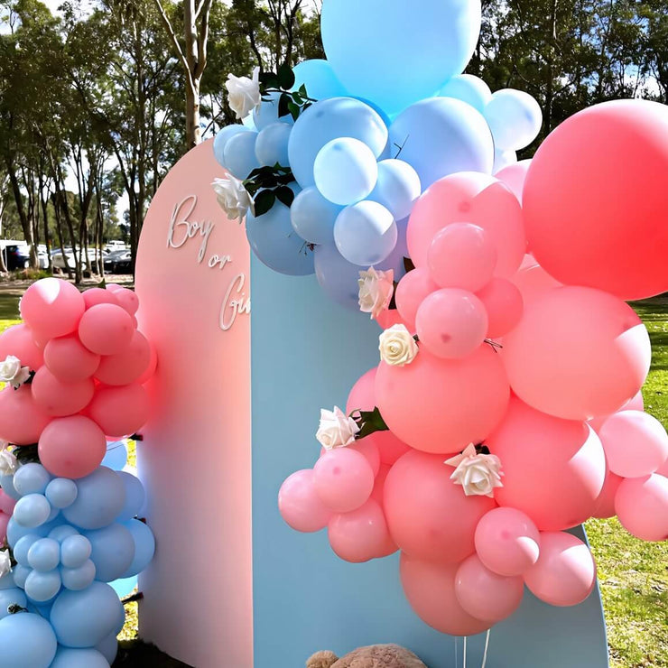 pink and blue backdrops with balloon garlands at gender reveal party