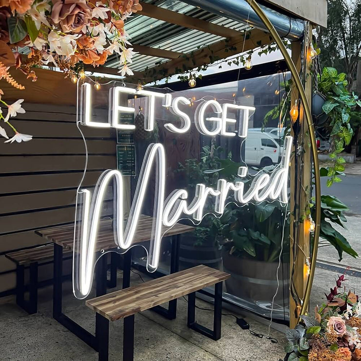 white lets get married neon sign hanging inside gold hoop backdrop