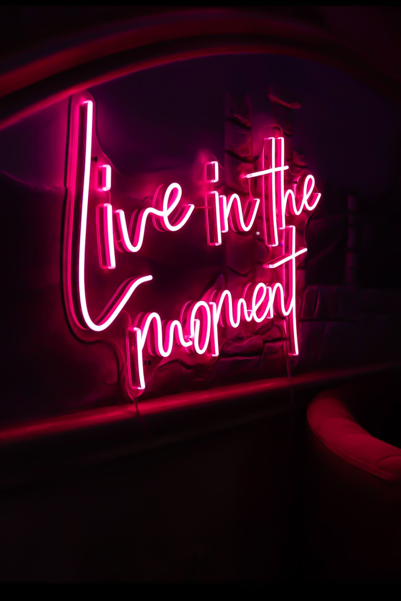 pink live in the moment neon sign hanging on bar wall