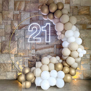 white 21 neon sign hanging on gold hoop backdrop with clear plinth and white and gold balloon arch