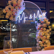 white mr and mrs neon sign hanging on white arch backdrop with flowers at sydney wedding