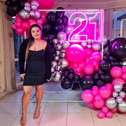 girl standing in front of hot pink 21 neon sign with balloon and frame backdrop
