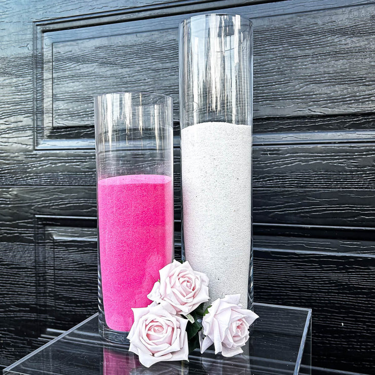 pink and white sand candles placed on clear plinth next to dusty pink roses