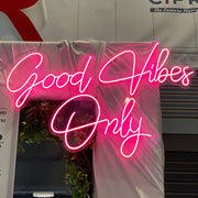 hot pink good vibes only neon sign hanging on white wall at event