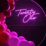 pink twenty one neon sign hanging on white mesh backdrop frame with balloons