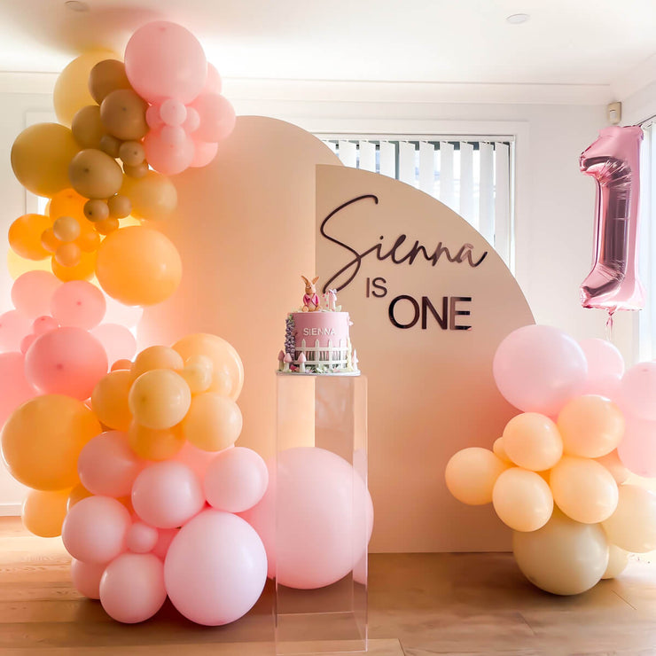 beige arch backrop setup with pink and peach balloons at child&