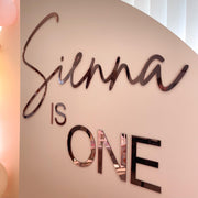rose gold acrylic lettering attached to beige backdrop board