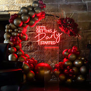 red lets get this party started neon sign hanging on black circle backdrop frame with balloons and flowers