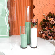 green and white coloured sand candles in clear vases with terracotta backdrops