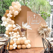 boho flower arrangement and balloons hanging on beige backdrops at outdoor baptism event