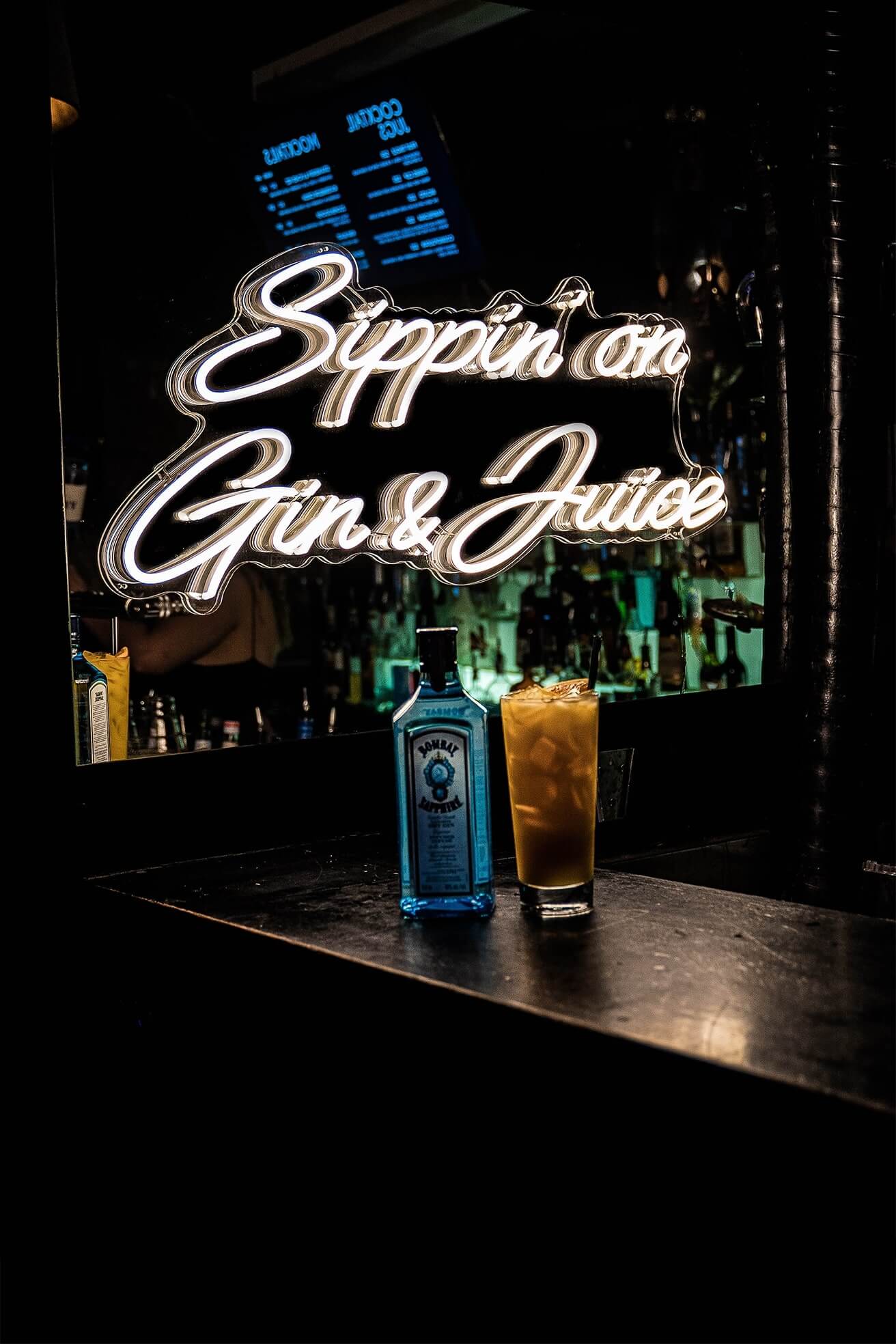 warm white sipping on gin and juice neon sign hanging inside bar