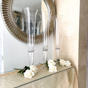 three tall wedding glass vases placed on glass table with white real touch roses