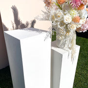 vase flower arrangement standing on top of white limestone plinth