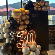 warm white 30 neon sign placed on black, gold and silver balloons at boys 30th birthday party