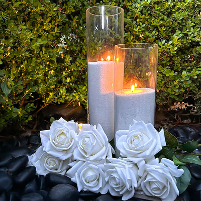 white sand candles placed in garden bed with white roses