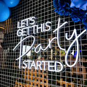 white let's get this party started neon sign hanging on white mesh backdrop with blue flowers and balloons