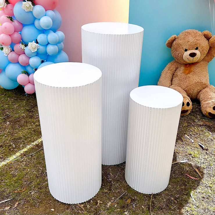three white ripple plinths standing on grass in front of gender reveal backdrop