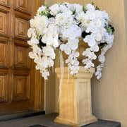 white rose and white orchid wedding arrangement placed on pillar outside house