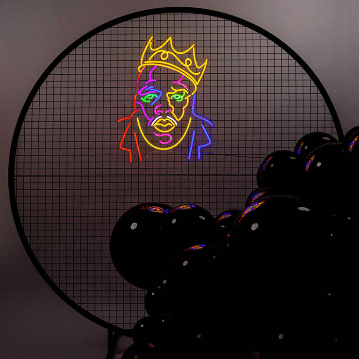 multicoloured biggie neon sign hanging on black mesh backdrop frame with black balloons