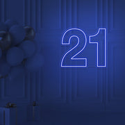 blue  21 neon sign hanging on wall with balloons