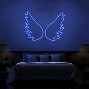 blue angel wings neon sign hanging on bedroom wall