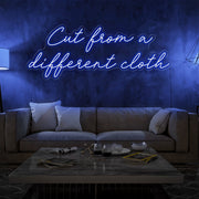 blue cut from a different cloth neon sign hanging on living room wall