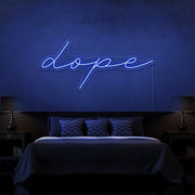 blue dope cursive neon sign hanging on bedroom wall
