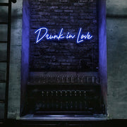 blue drunk in love neon sign hanging on bar wall