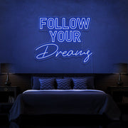 blue follow your dreams neon sign hanging on bedroom wall
