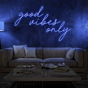 blue good vibes only neon sign hanging on living room wall