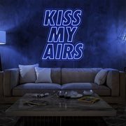 blue kiss my airs neon sign hanging on living room wall