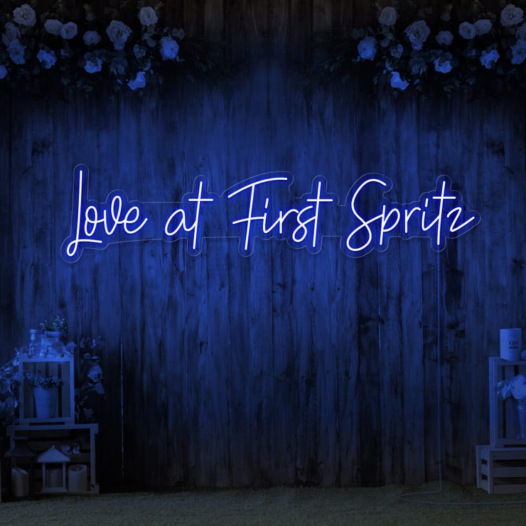 blue love at first spritz neon sign hanging on timber wall