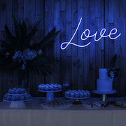 blue love neon sign hanging on timber wall above dessert table