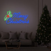 blue merry chirstmas mistletoe neon sign hanging above couch next to christmas tree
