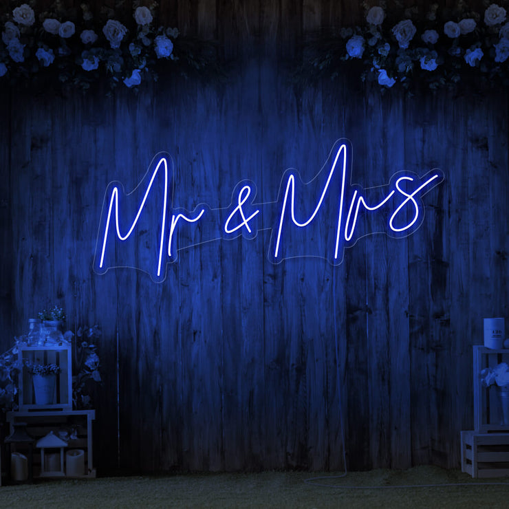 blue mr and mrs neon sign hanging on wall with flowers