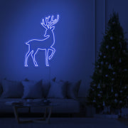 blue reindeer neon sign hanging on living room wall next to christmas tree