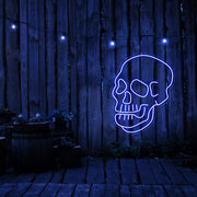 blue skull neon sign hanging on timber fence