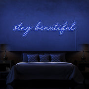 blue stay beautiful neon sign hanging on bedroom wall