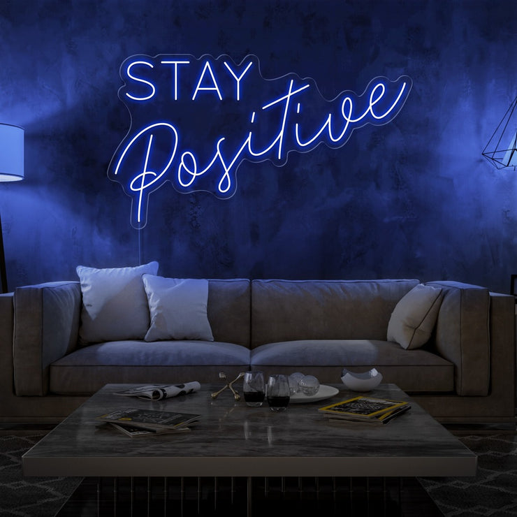 blue stay positive neon sign hanging on living room wall