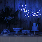 blue til death neon sign hanging on timber wall above dessert table