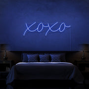 blue xoxo neon sign hanging on bedroom wall